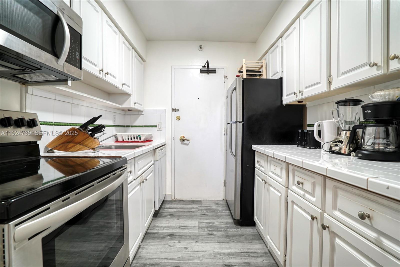 5225 Collins Avenue, Unit 1204 Miami Beach, FL 33140 - Photo 33 of 49 a kitchen with stainless steel appliances a stove a sink and cabinets