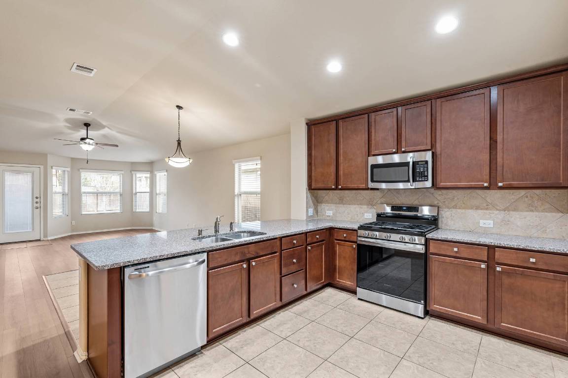 180 Fletcher Bend Buda, TX 78610 - Photo 12 of 36 a kitchen with stainless steel appliances granite countertop a sink and stove top oven