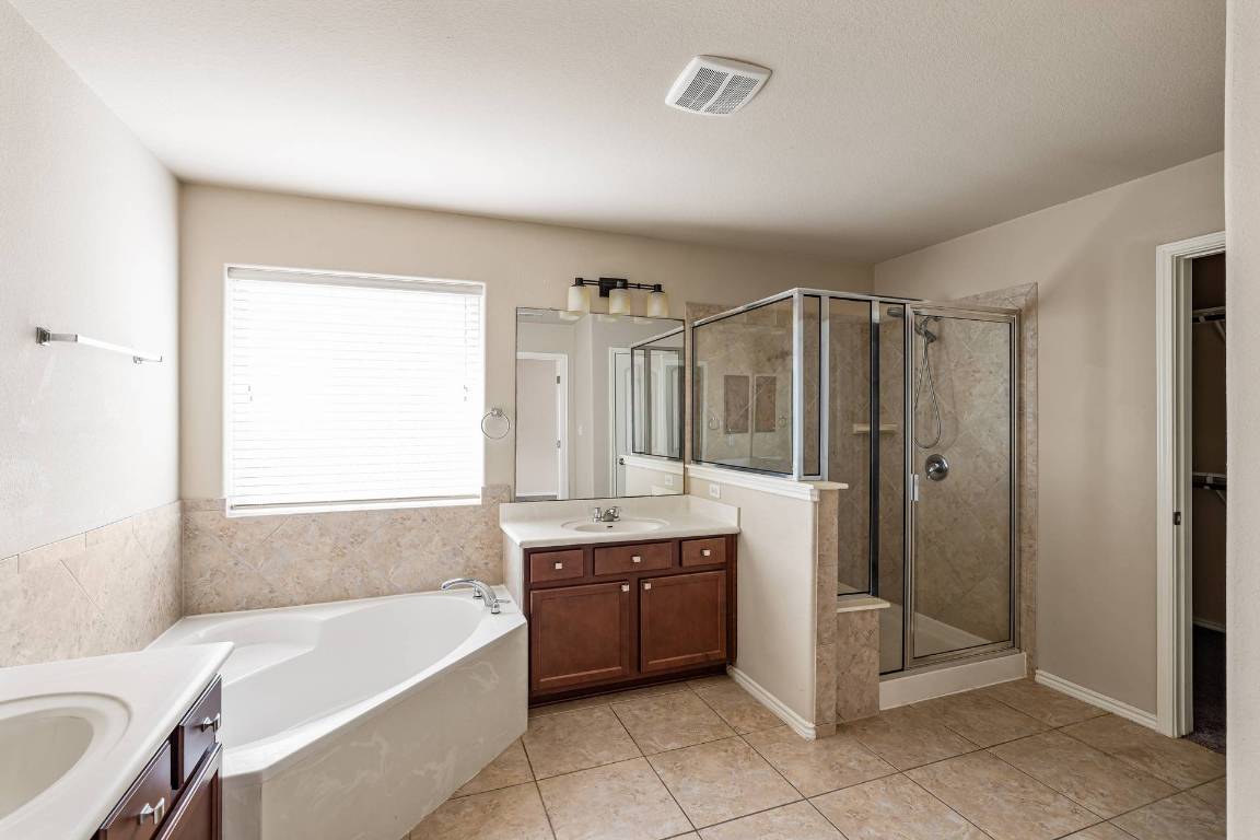 180 Fletcher Bend Buda, TX 78610 - Photo 19 of 36 a bathroom with a tub sink and mirror
