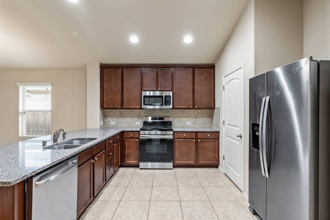 180 Fletcher Bend Buda, TX 78610 - Photo 9 of 36 a kitchen with stainless steel appliances granite countertop a refrigerator stove a sink and dishwasher