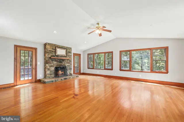 a view of empty room with wooden floor and fan