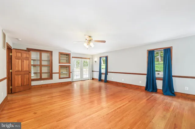 a view of an empty room with window and wooden floor