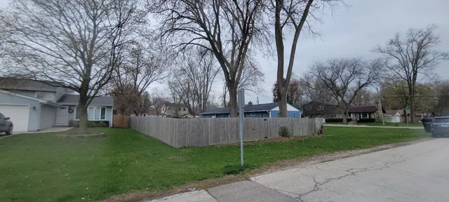 a view of a white house next to a yard and large trees