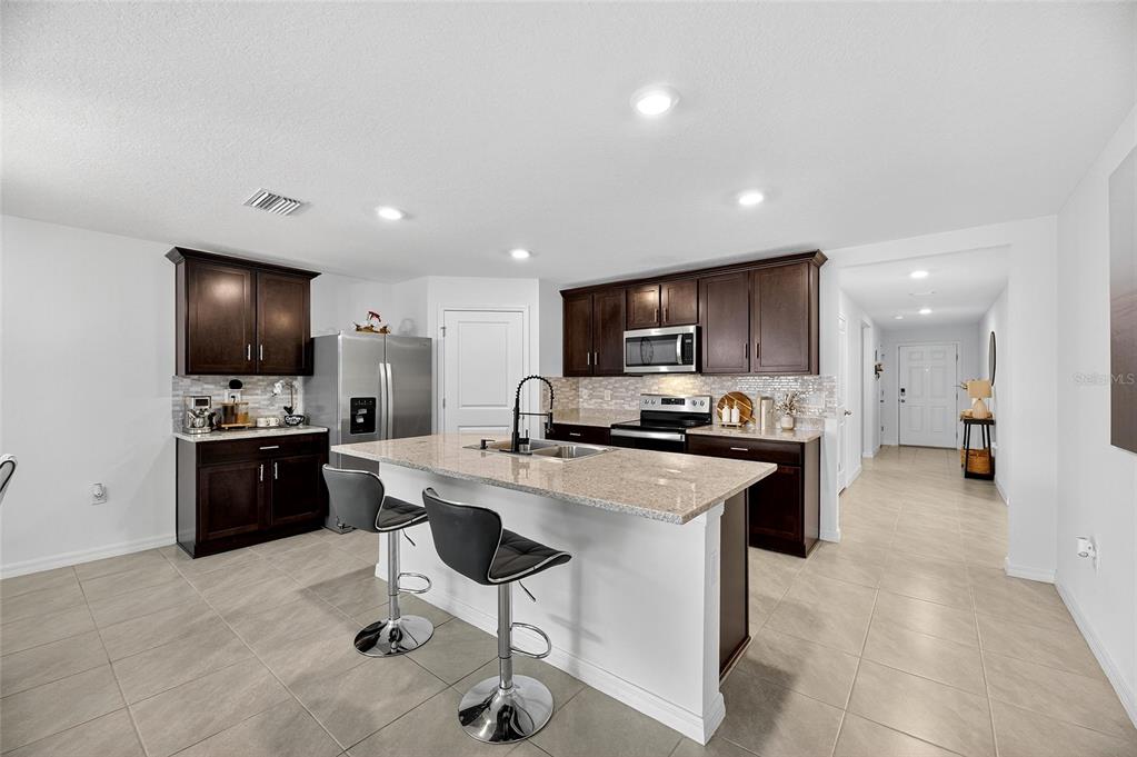 3602 Forest Path Drive Plant City, FL 33565 - Photo 29 of 75 a kitchen with stainless steel appliances a stove a sink a microwave a refrigerator and chairs