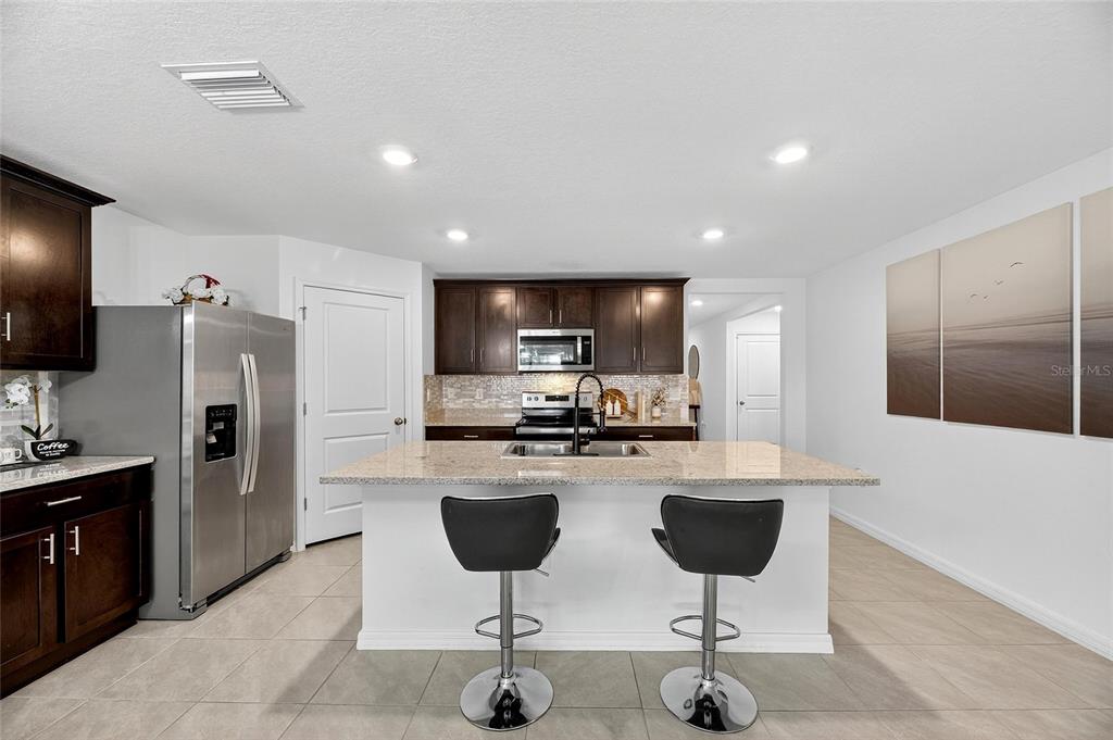 3602 Forest Path Drive Plant City, FL 33565 - Photo 30 of 75 a kitchen with stainless steel appliances kitchen island granite countertop a refrigerator and a stove top oven