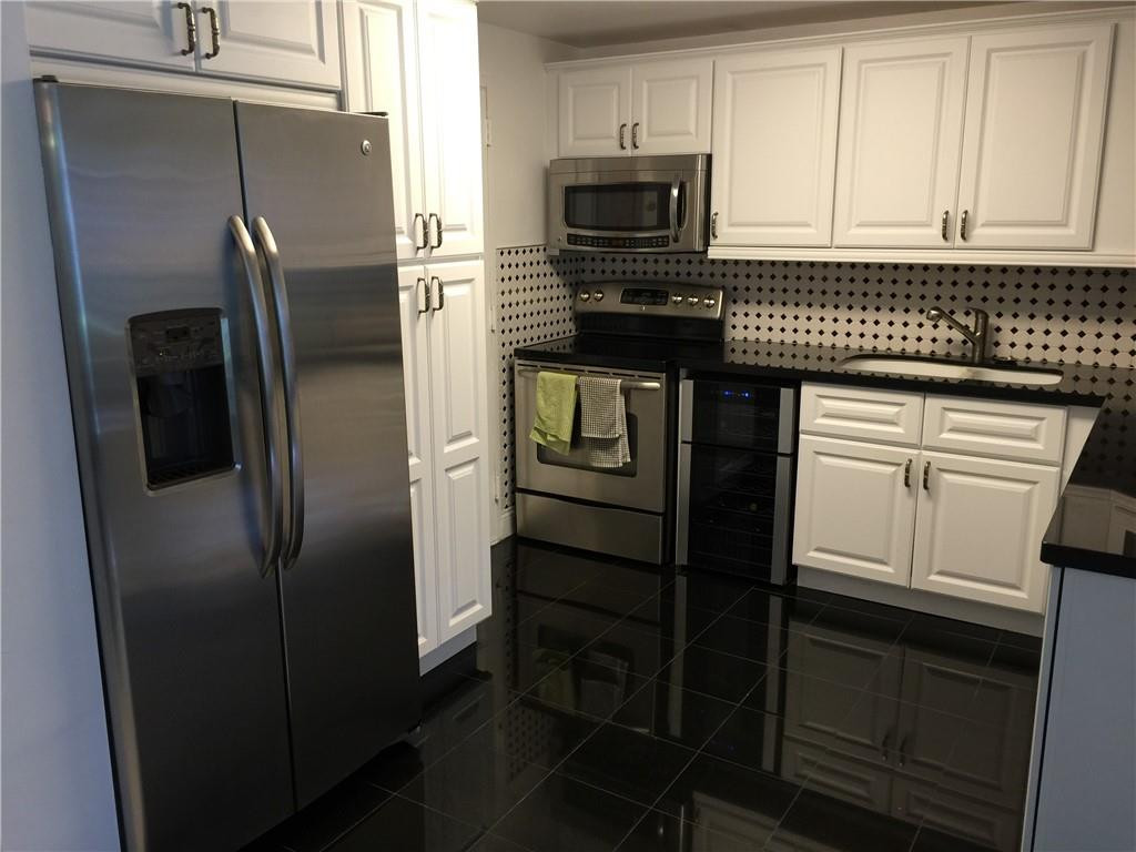 3670 Inverrary Drive, Unit 1E Lauderhill, FL 33319 - Photo 5 of 15 a kitchen with granite countertop stainless steel appliances and wooden cabinets