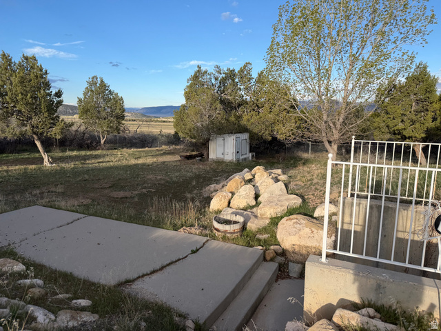10000 North 6730th East Spring City, UT 84662 - Photo 2 of 31 Expansive outdoor area featuring a concrete patio, mature trees, and natural rock landscaping elements