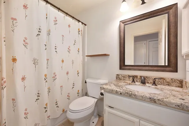 a bathroom with a granite countertop sink toilet and mirror