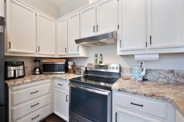 a kitchen with granite countertop white cabinets and white appliances