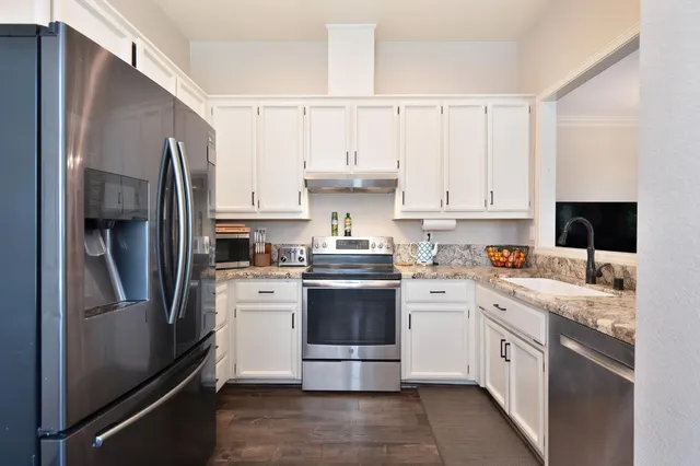 a kitchen with stainless steel appliances granite countertop a refrigerator stove and sink