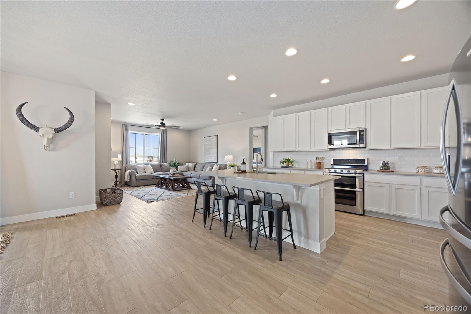 12649 Buffington Trail Parker, CO 80134 - Photo 8 of 47 a large white kitchen with lots of counter space a sink dining table and chairs