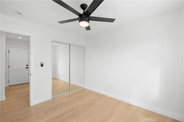 an empty room with wooden floor and a ceiling fan