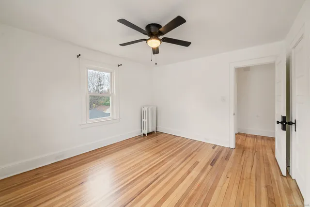 a view of empty room with wooden floor and ceiling fan