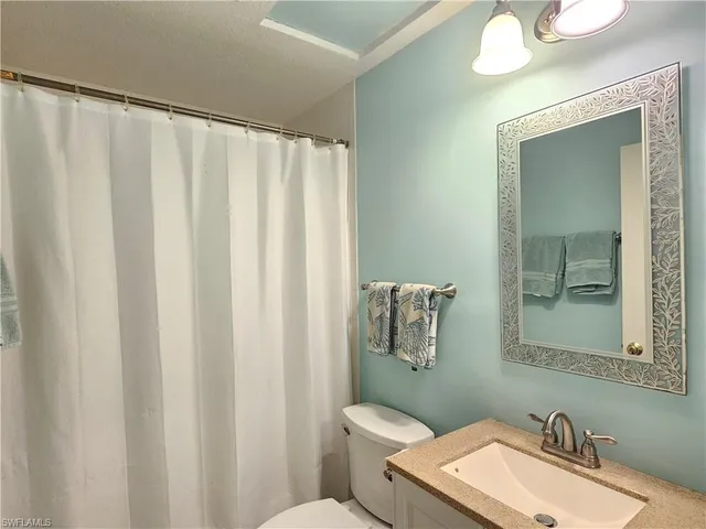 a bathroom with a sink a toilet and shower curtain