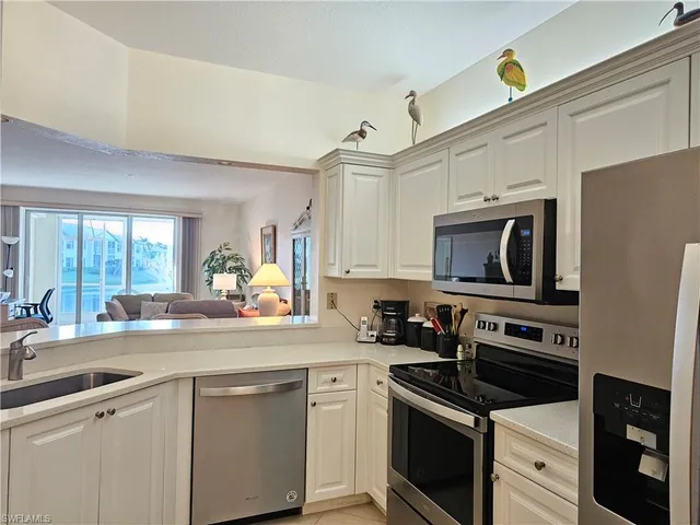 a kitchen with cabinets stainless steel appliances and a window