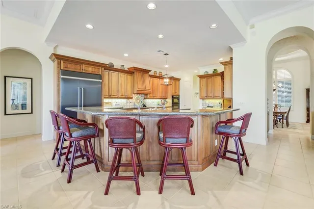 a kitchen with stainless steel appliances kitchen island granite countertop a dining table chairs and sink