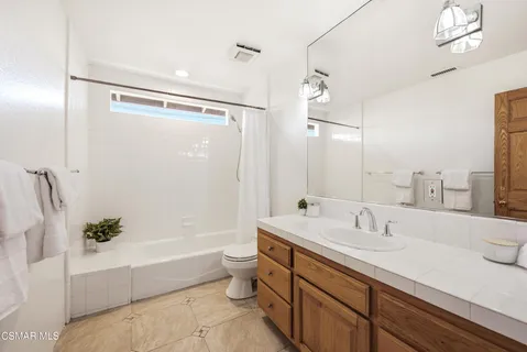 a bathroom with a bathtub shower sink vanity and toilet