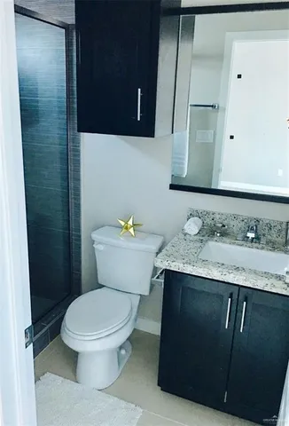 a bathroom with a granite countertop toilet sink and mirror