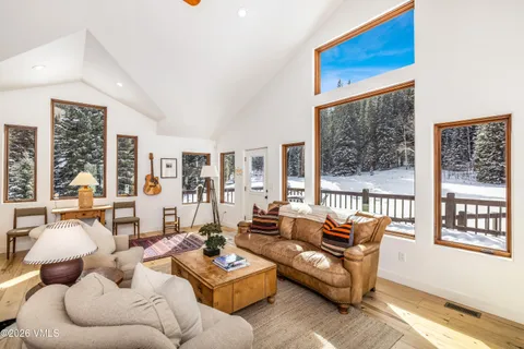 a view of a dining room and livingroom with furniture wooden floor a rug a fireplace and a chandelier
