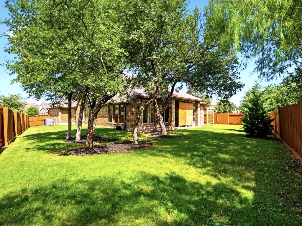 109 Lake Spring Circle Georgetown, TX 78633 - Photo 37 of 38 A verdant lawn provides a private outdoor retreat, framed by mature trees and a sturdy fence.