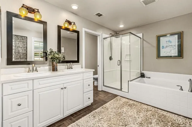 a spacious bathroom with a double vanity sink mirror and bathtub