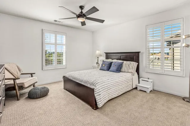 a bedroom with a bed a couch and a ceiling fan