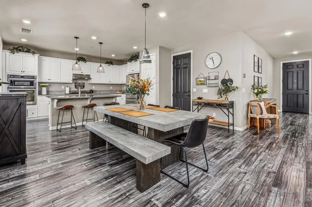 an open kitchen with wooden floor and stainless steel appliances