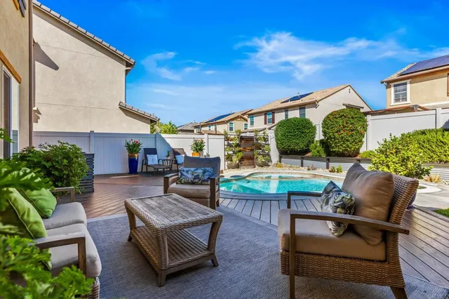 a view of a patio with couches table and chairs with potted plants and wooden fence