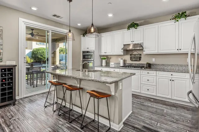 a kitchen with stainless steel appliances granite countertop a stove a sink dishwasher and a refrigerator with wooden floor