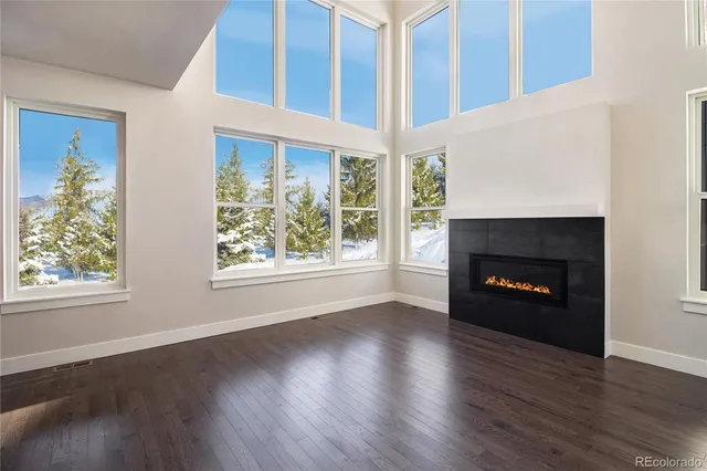 an empty room with wooden floor fireplace and windows