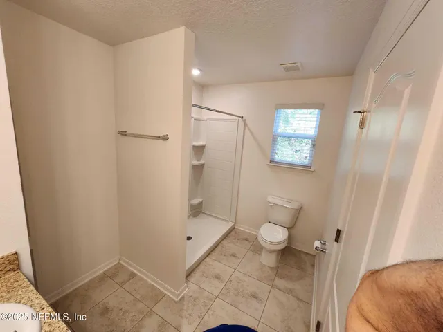 a bathroom with a granite countertop shower and a toilet