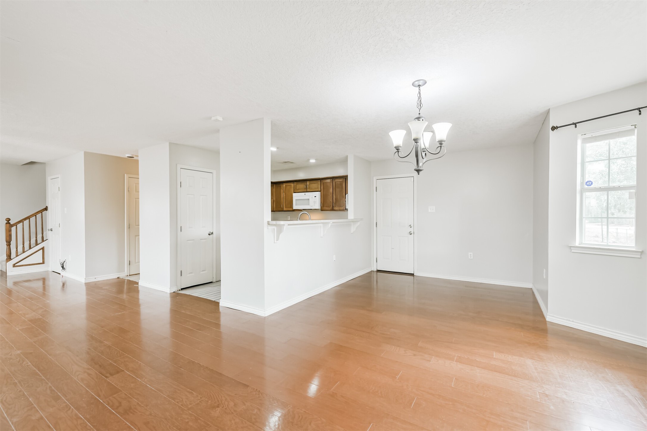 1103 Williams Street Cleveland, TX 77327 - Photo 19 of 32 an empty room with wooden floor chandelier and windows