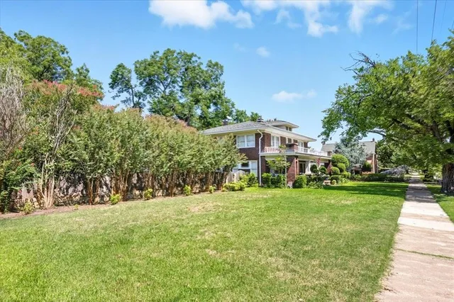 a view of a house with a big yard and large trees