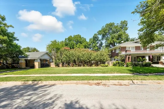 a front view of a house with a big yard and palm trees