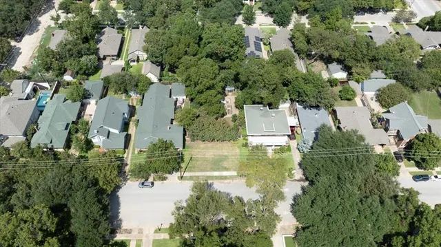 an aerial view of residential houses with outdoor space and trees