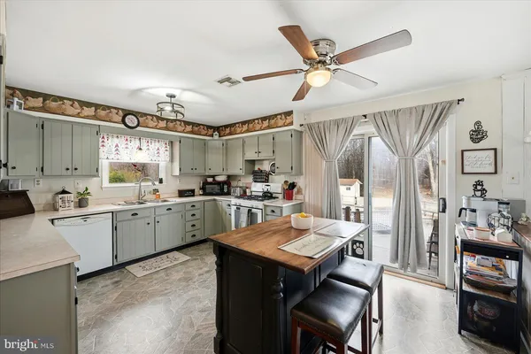 a open kitchen with a refrigerator a sink dishwasher a dining table and chairs with wooden floor