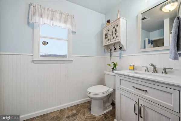 a bathroom with a toilet sink a mirror and vanity
