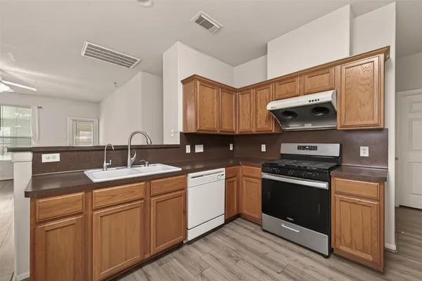 a kitchen with stainless steel appliances granite countertop a sink cabinets and wooden floor