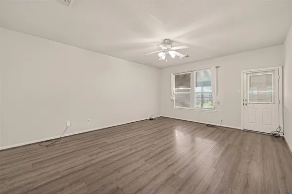 an empty room with wooden floor and windows