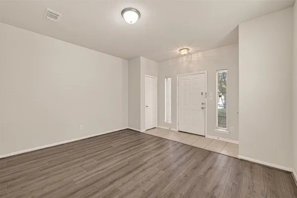 a view of an empty room with wooden floor and a window