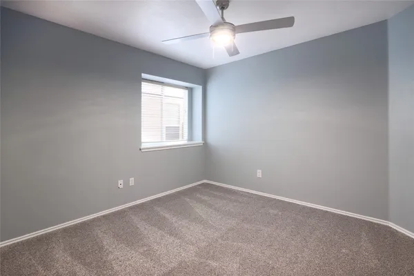 an empty room with a window and chandelier fan