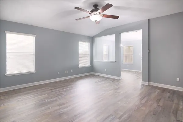 a view of an empty room with a window and wooden floor