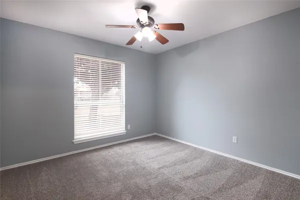 an empty room with windows and chandelier fan