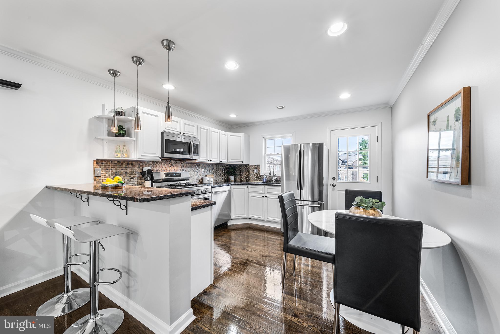 5202 Ridge Avenue Philadelphia, PA 19128 - Photo 4 of 30 a kitchen with stainless steel appliances granite countertop a refrigerator oven a sink dishwasher a dining table and chairs with wooden floor