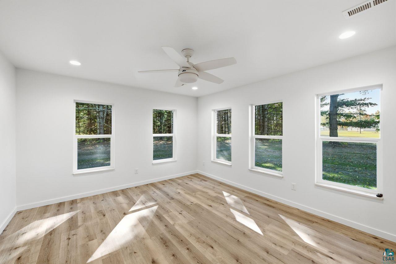 65352 Adler Road Marengo, WI 54855 - Photo 7 of 24 Recessed lighting, wood-finish flooring, white walls, multiple windows, and a ceiling fan