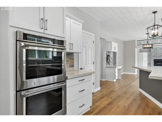 a kitchen with stainless steel appliances white cabinets and wooden floors