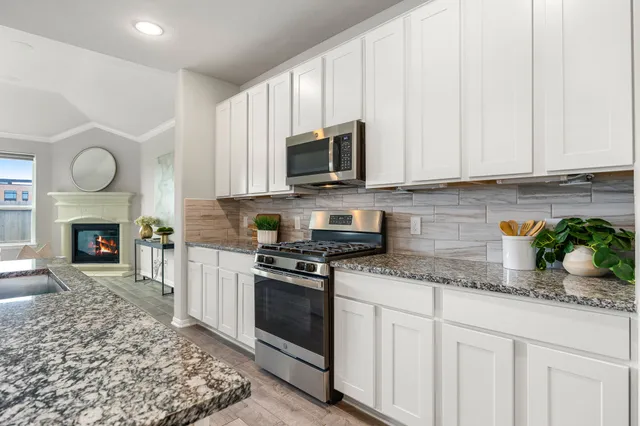 a kitchen with granite countertop a stove sink and cabinets