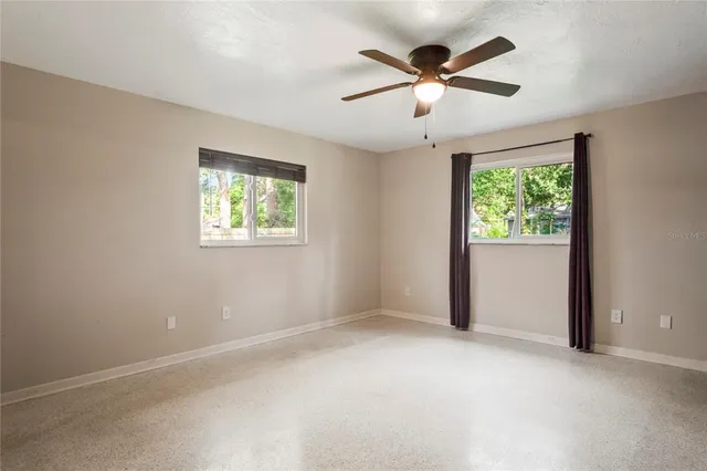 an empty room with windows and fan