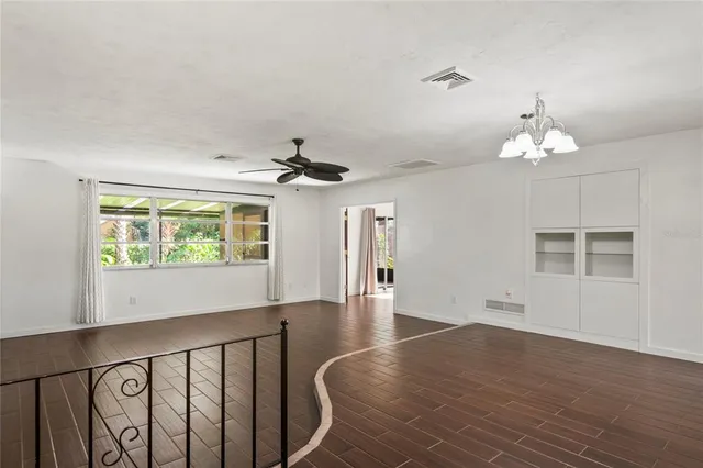 a view of an empty room with a window and wooden floor