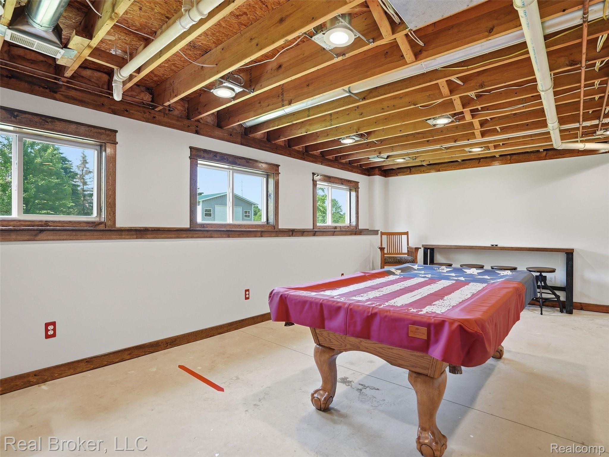 7271 West Ray Road Gaines, MI 48436 - Photo 41 of 48 Finished basement space featuring multiple windows, exposed wooden ceiling beams, recessed lighting fixtures, and a long built-in bar table